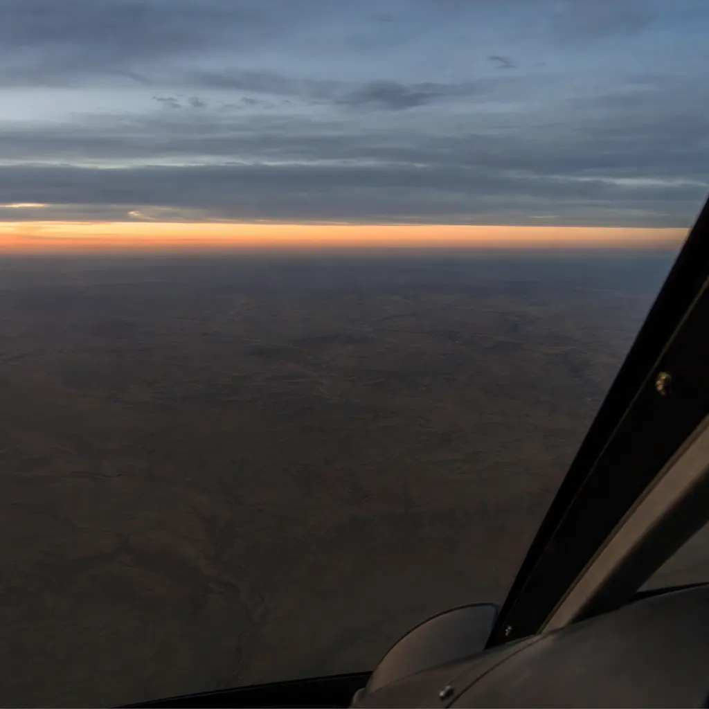 Featureless desert terrain seen from a high vantage at dusk, with no roads or landmarks in view.