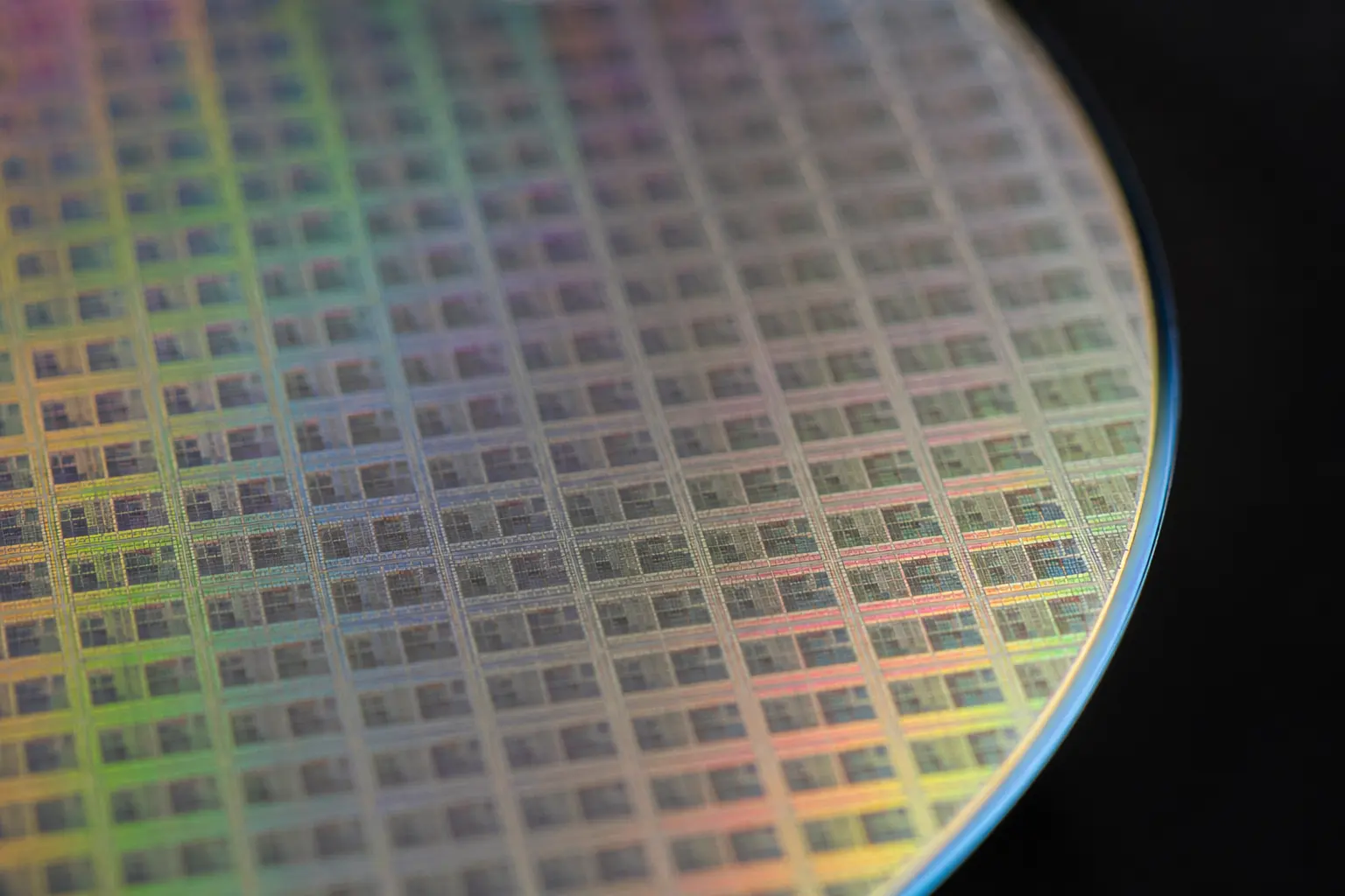 Extreme macro of a polished semiconductor wafer surface at a shallow angle, showing a repeating grid of die.